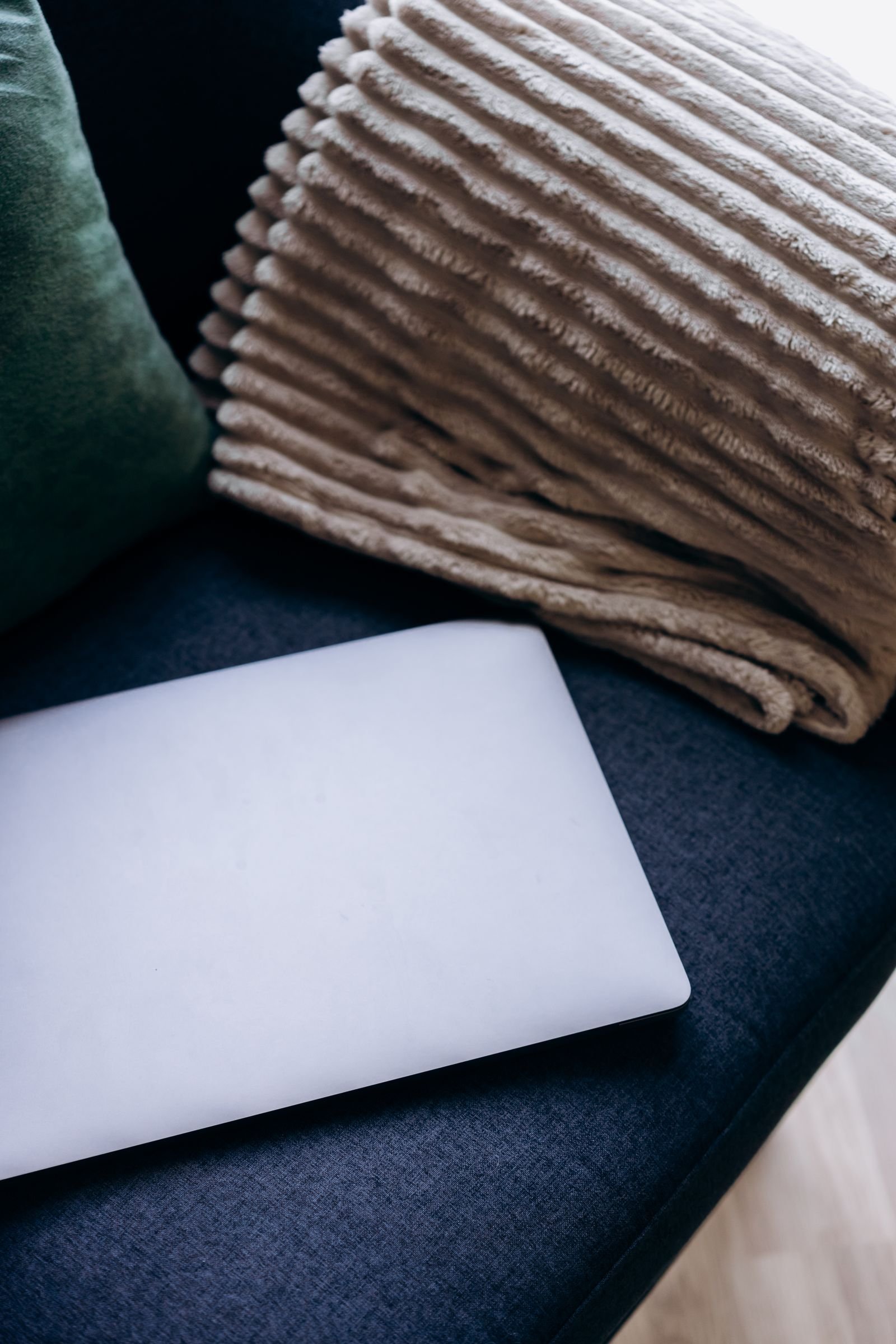 Top view of a laptop on a cozy couch with a soft ribbed blanket