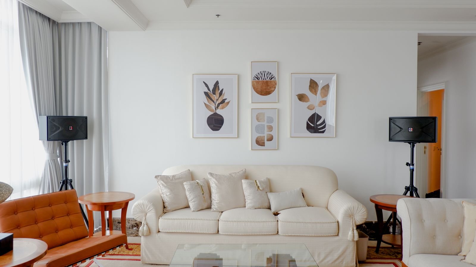 A neutral living room with botanical art prints arranged above a white sofa