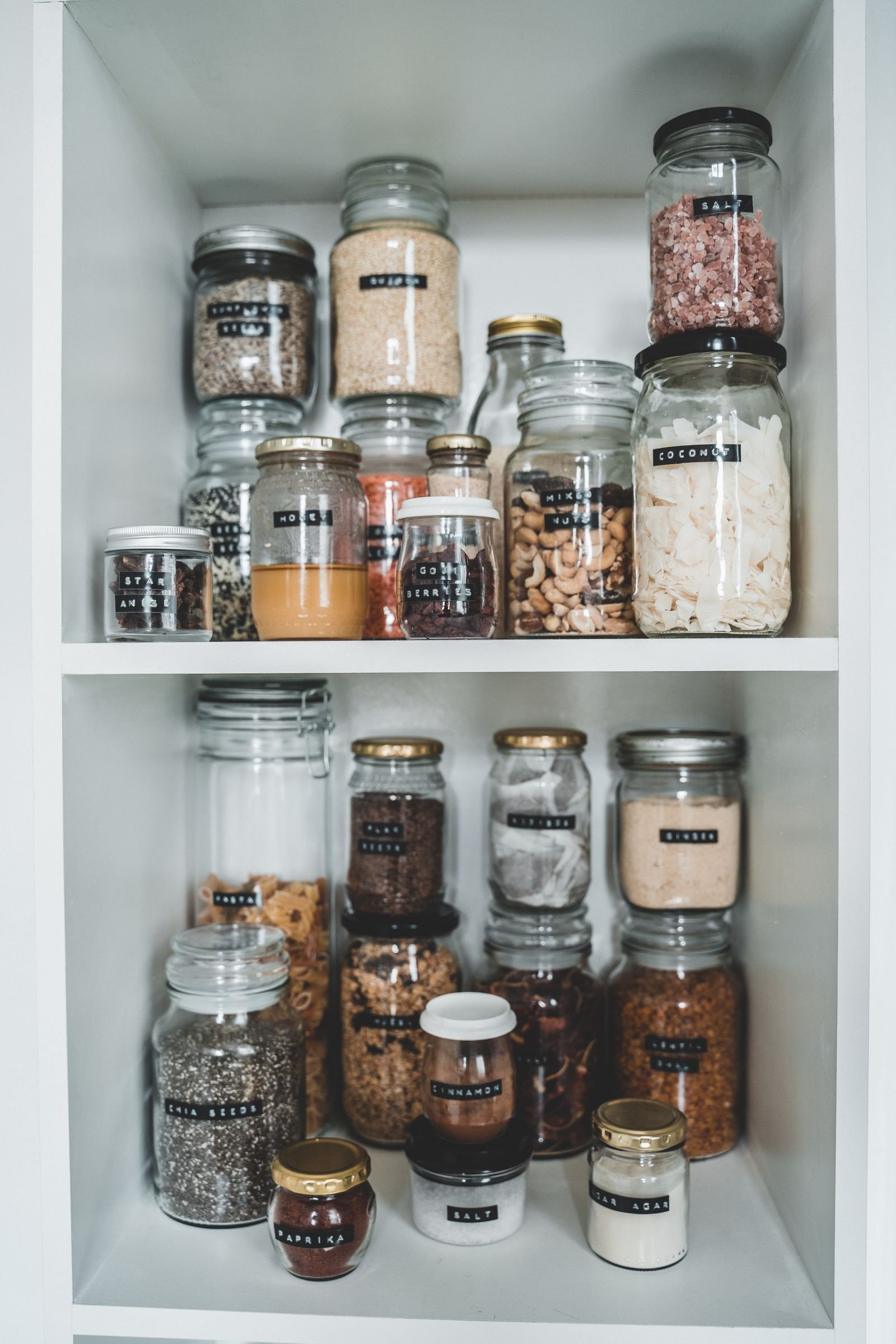 White shelves with neatly arranged glass jars of pantry staples