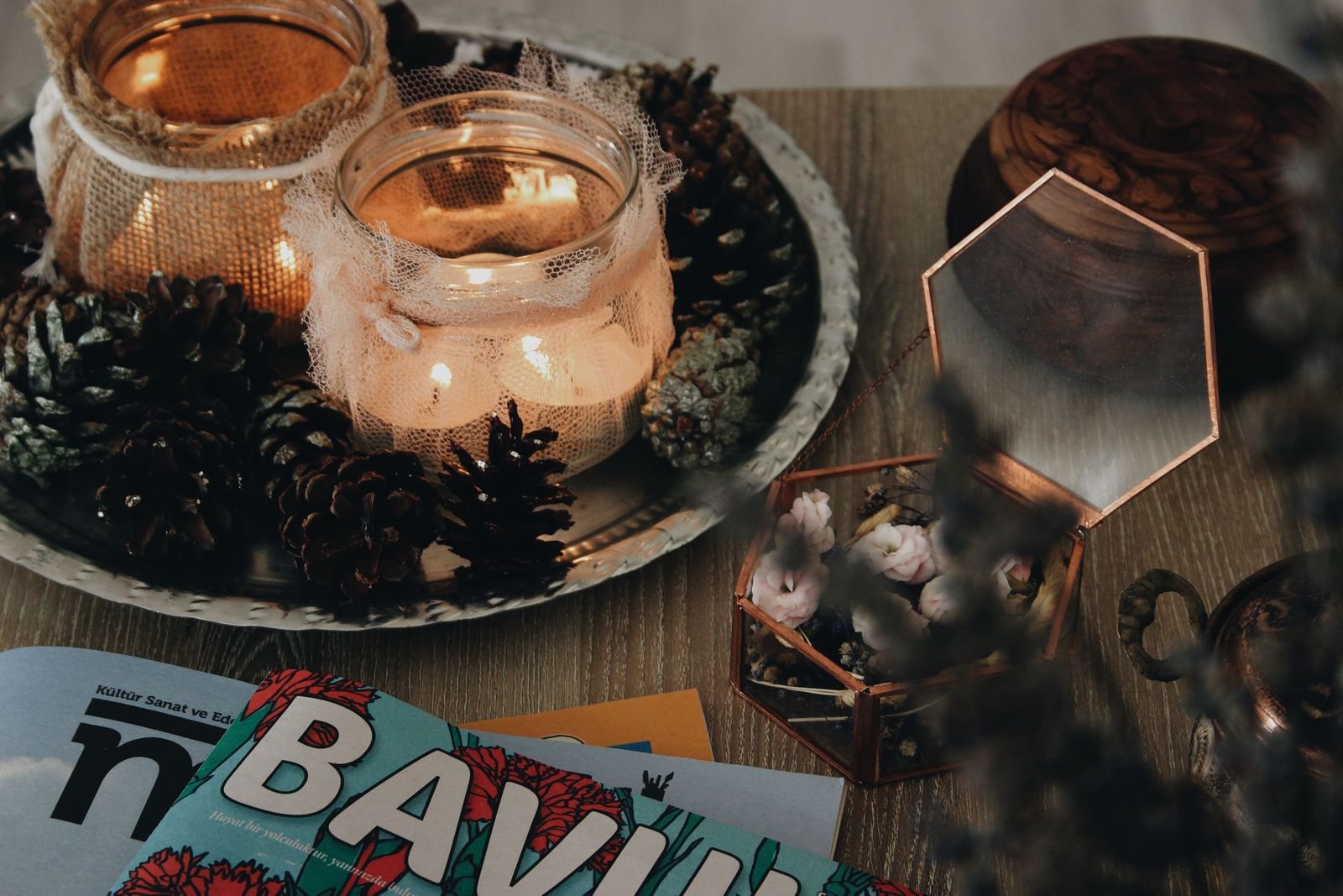 Lit candles in glass holders surrounded by pinecones on a tray for cozy winter decor